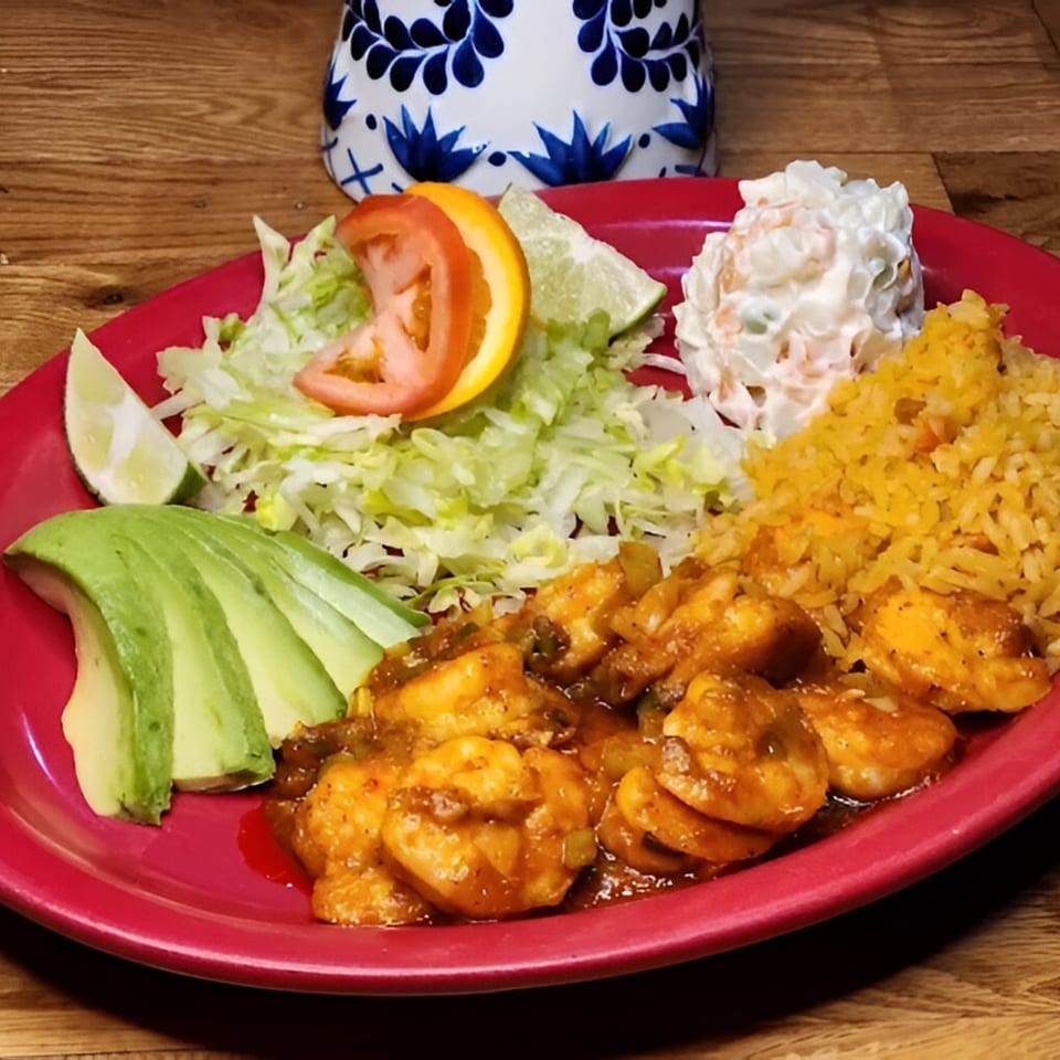 Taxco Mexican Cuisine's shrimp dish with rice, avocado, salad, and coleslaw on a red plate.