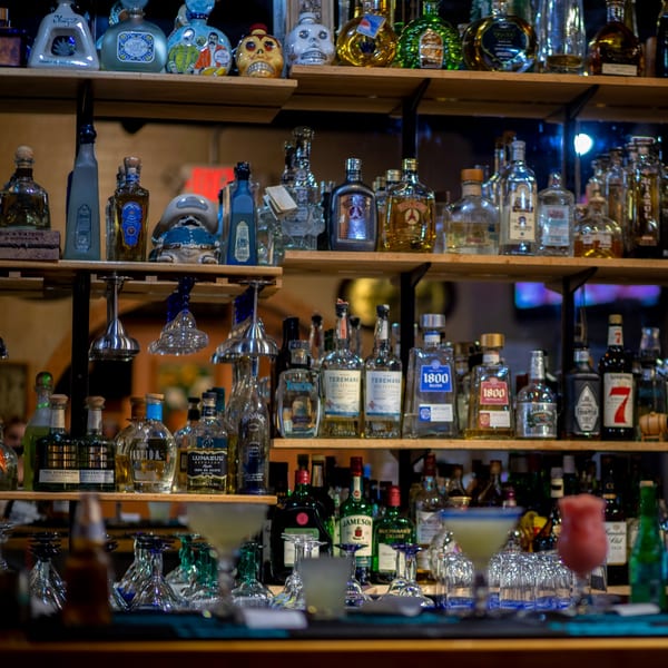 A well-stocked bar at Taxco Mexican Cuisine with various tequila bottles and margaritas on the counter.