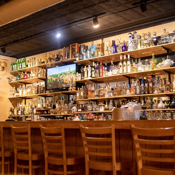 A well-stocked bar at Taxco Mexican Cuisine, featuring numerous tequila bottles and a TV screen.