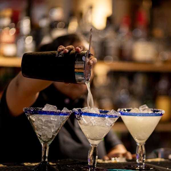 A bartender pours a margarita from a shaker into a salt-rimmed glass at Taxco Mexican Cuisine.